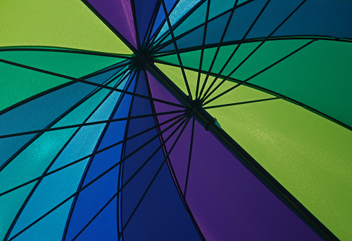 Detail of a colorful open umbrella watched from underneath while sunshine