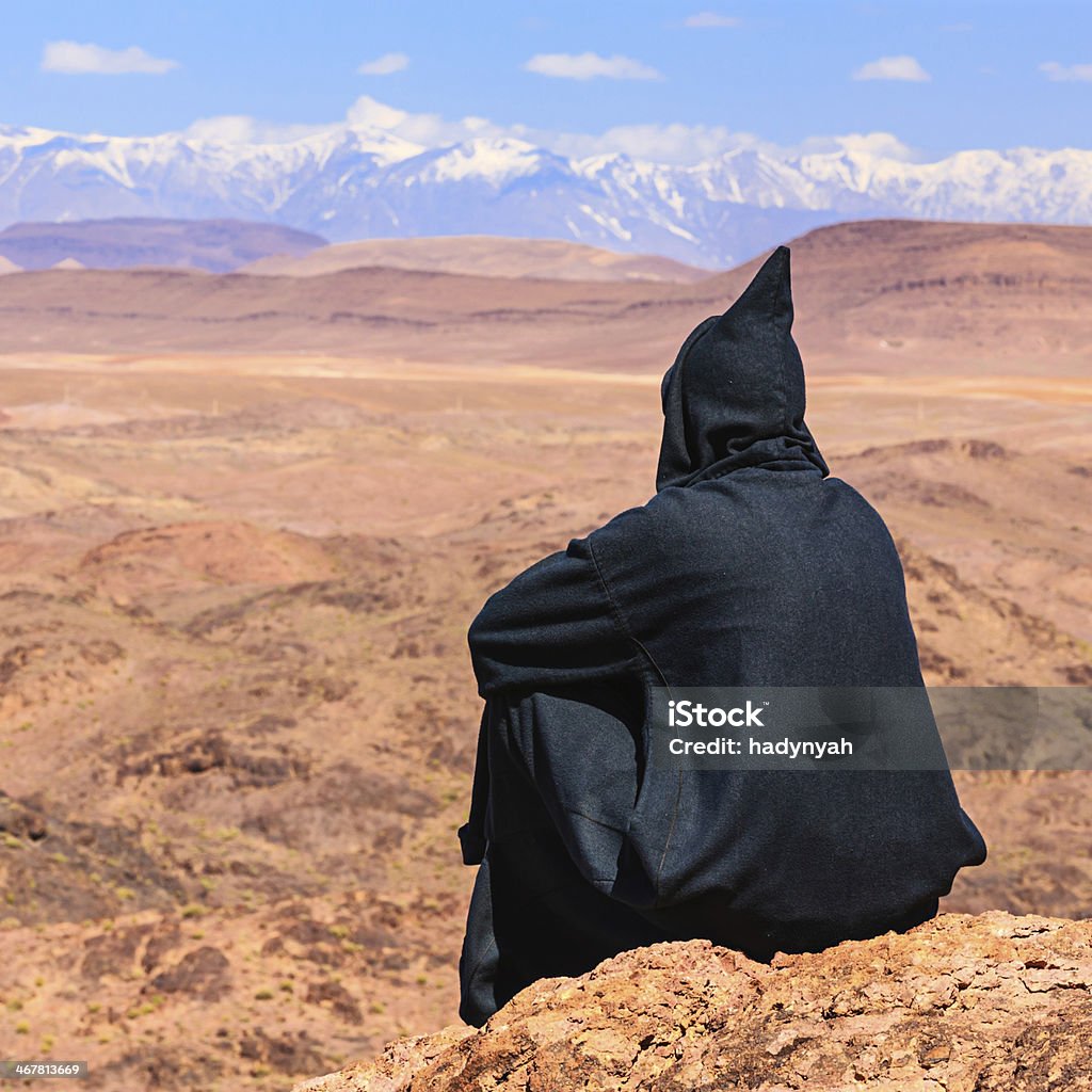 Maroccan man looking at High Atlas mountain range The High Atlas rises in the west at the Atlantic Ocean and stretches in an eastern direction to the Moroccan-Algerian border. Jbel Toubkal is the highest peak (4167m) in the range.http://bem.2be.pl/IS/morocco_380.jpg Desert Area Stock Photo