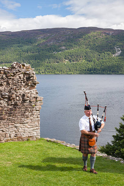 castello di urquhart, highlander con kilt scozzes'e riproduzione di cornamusa - scotland castle loch ness urquhart castle foto e immagini stock