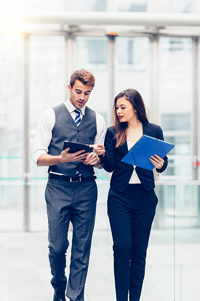 istock Smart woman holding clipboard pointing at tablet held by man 467818054