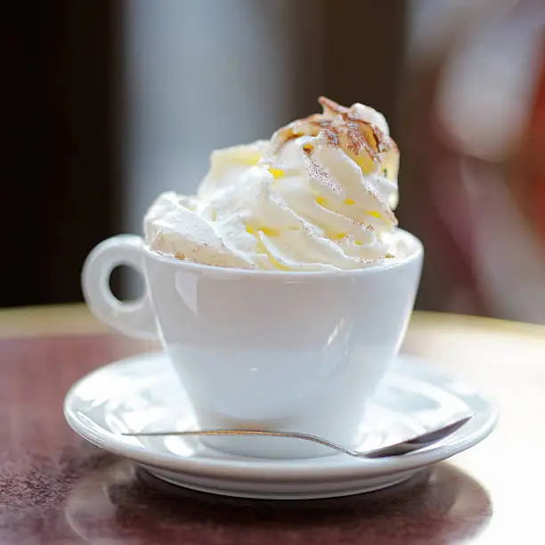 Cup of coffee or hot chocolate with whipped cream on the table at the cafe