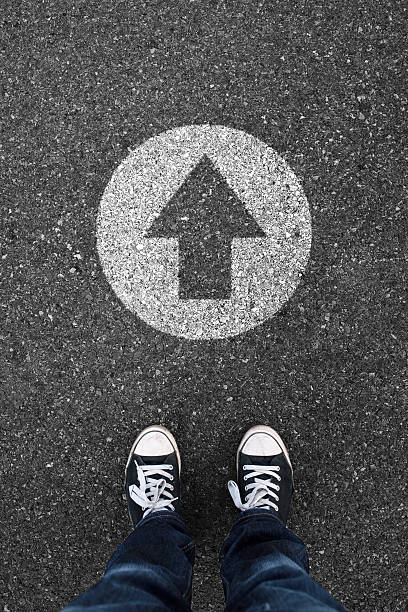 istock Shell toed sneakers and a chalk arrow circle on asphalt 467819882