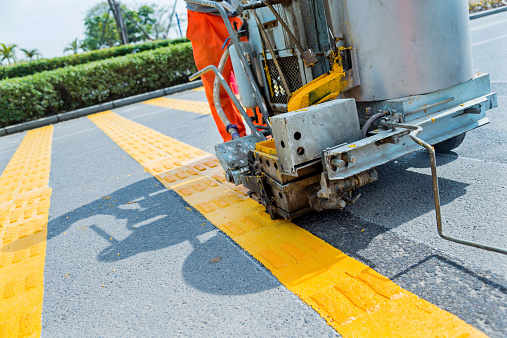 Pavement marker machine spraying yellow lines at a urban road.