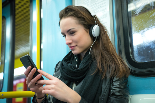 Beautiful woman listening to music on subway train.