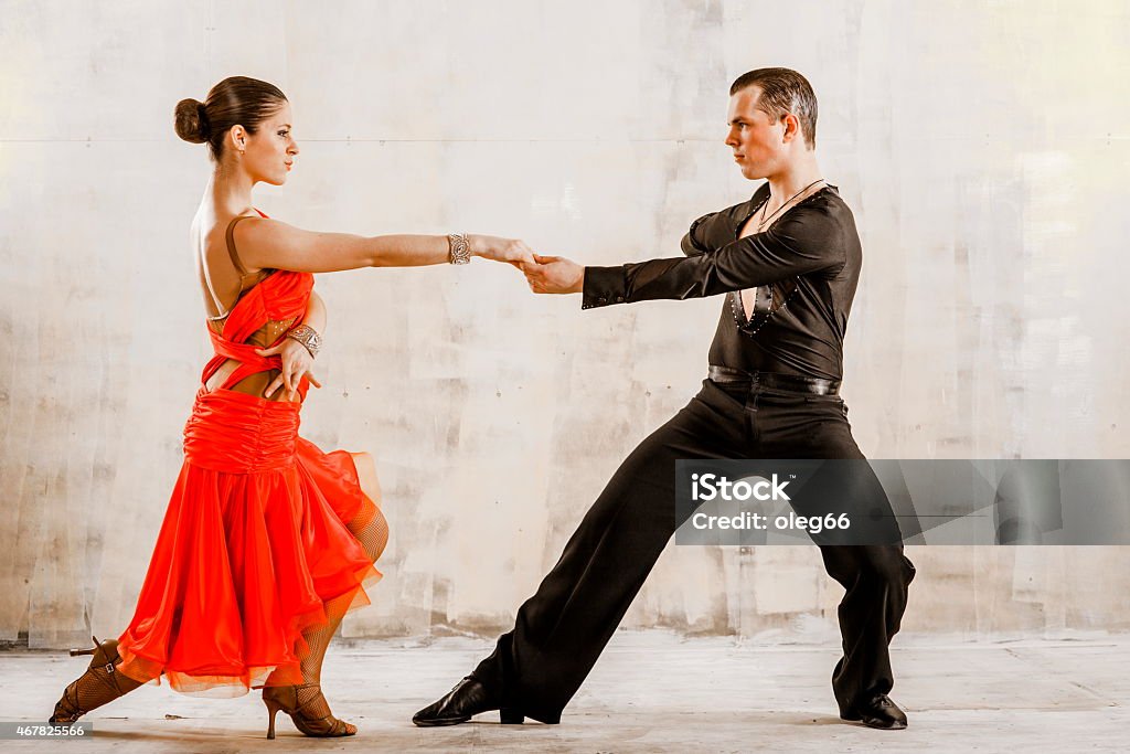 pair of dancers dancing in the studio on a light background young couple, Latin American dances, samba, cha-cha-cha, rumba, paso doble, jive, the girl dressed in red beautiful dress, they cheerful, funny Paso Doble Stock Photo