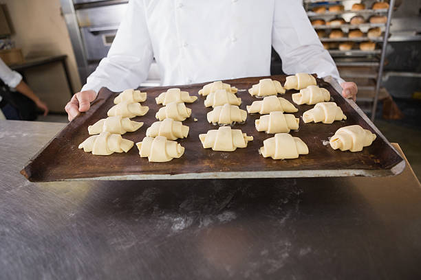 istock Close up baker holding tray of raw dough 467826174