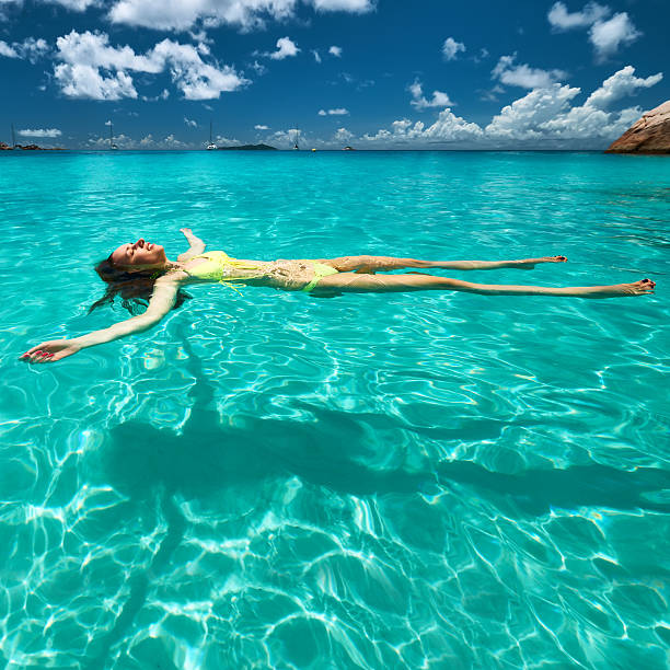 istock Woman in yellow bikini lying on water 467838292