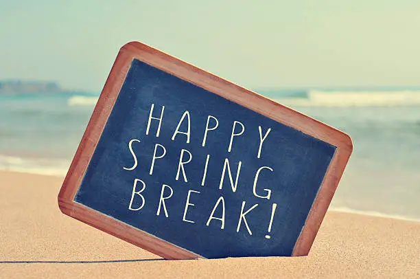 Photo of happy spring break in a blackboard on the beach