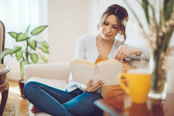 hermosa mujer latina leyendo un libro en su hogar - living room elegance women long hair fotografías e imágenes de stock