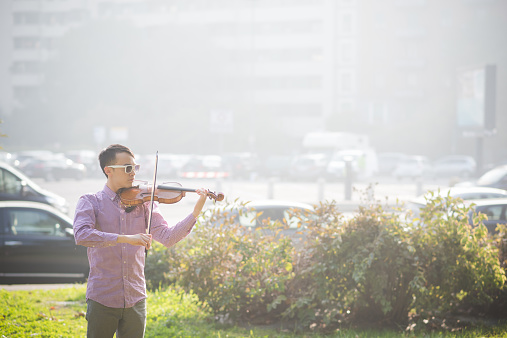 young crazy funny musician violinist asian man in town outdoor lifestyle