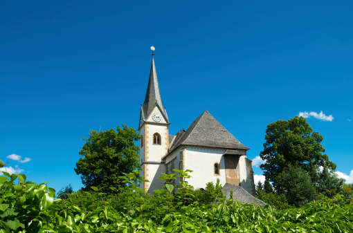 exterior of the church in Maria Worth, Austria. A first St. Mary's Church was erected about 875 during the Christianization of Carinthia.  Today's parish church Saints Primus and Felician stands on the highest point of the peninsula, with the neighbouring Winterkirche beneath it.