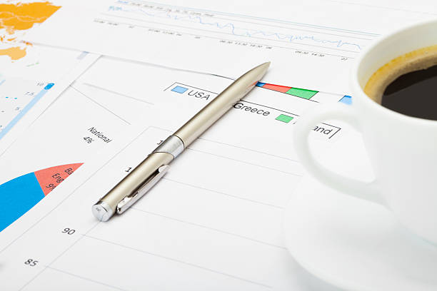 istock Coffee cup and pen over financial charts 467858864