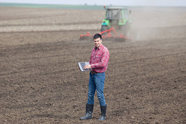 istock Farmer with laptop and tractor 467859242