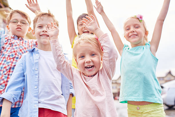 Absolutely happy kids Group of excited kids raising arms up and laughing childrens day photos stock pictures, royalty-free photos & images