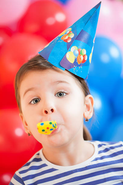 istock 3 years old girl with party horn blower 467862020