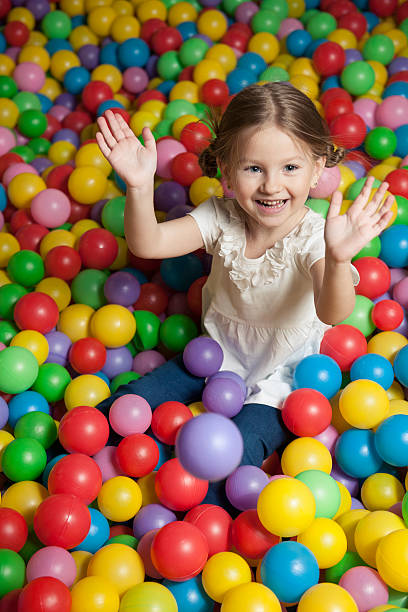 istock Young girl in ball pit throwing colored balls 467867431
