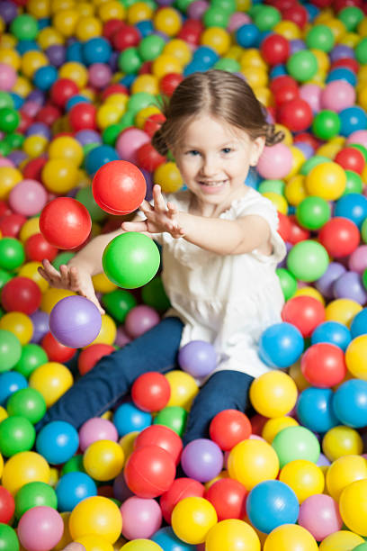 istock Young girl in ball pit throwing colored balls 467867441