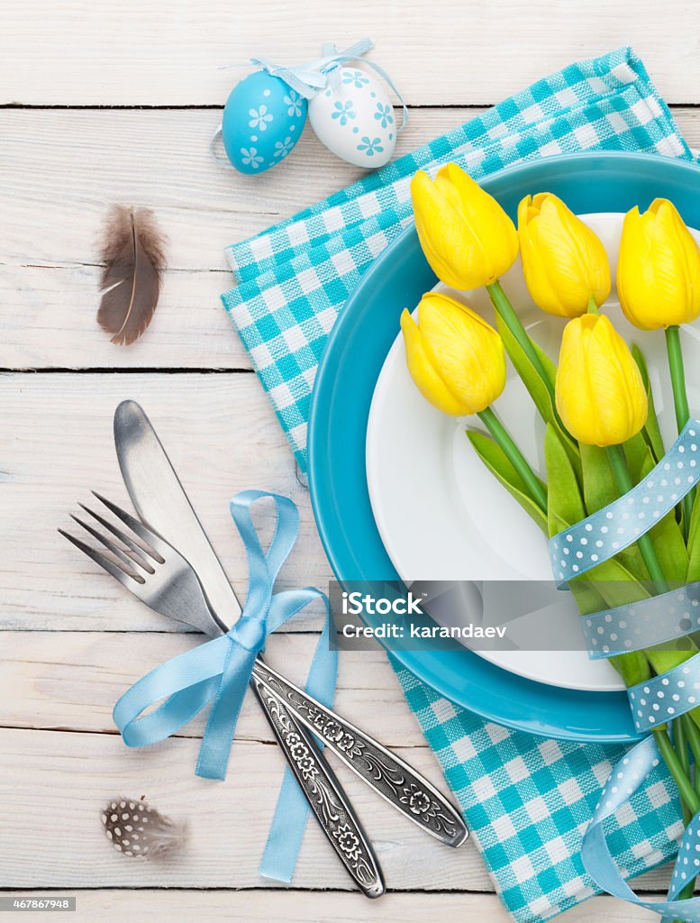 Easter with yellow tulips and colorful eggs Easter with yellow tulips and colorful eggs over white wooden table. Top view 2015 Stock Photo