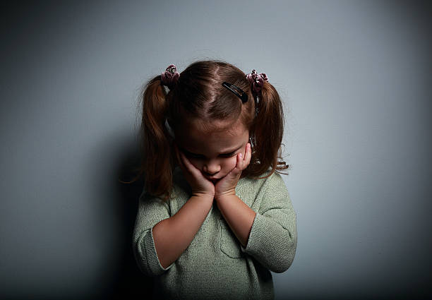 chorar criança menina segurando as mãos e rosto olhar para baixo - displeased child abandoned child abuse imagens e fotografias de stock