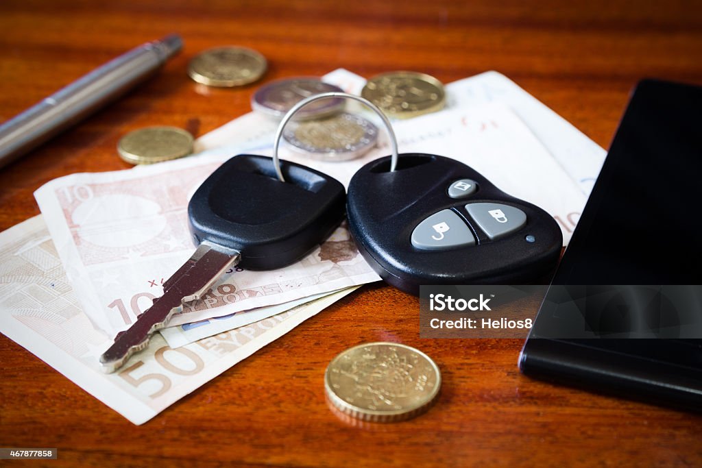 car keys, phone and money the contents of the pockets of men on a brown wooden table 2015 Stock Photo