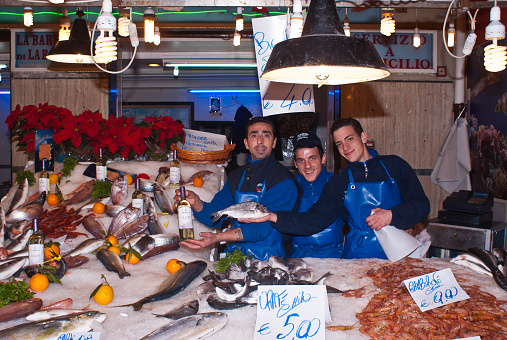 Palermo, Italy - December 22, 2012: men selling fish on the local market in Palermo, called Ballaro. This market is also tourist attraction in Palermo, Sicily.