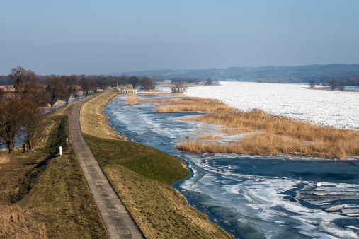 Winter flood at the Oder River in February 2014. The Oder River is a border river between Poland and Germany. The river is frozen and in the center accumulates drift ice. View to the north near the little German village Stützkow.