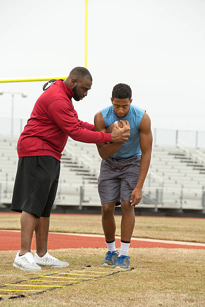 istock Coach training a high school athlete for football. 467890206