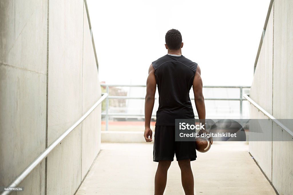 Rear view of an African American teenager holding a football. Silhouete of an African American teenager holding a football. Athlete Stock Photo