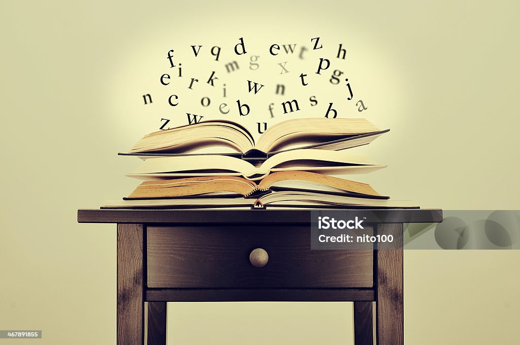 literature or knowledge a pile of books and letters floating over them on a desk symbolizing the idea of literature or knowledge Adventure Stock Photo