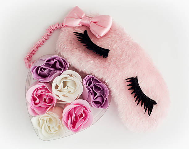 Pink sleeping mask and little heart made of fabric flowers stock photo