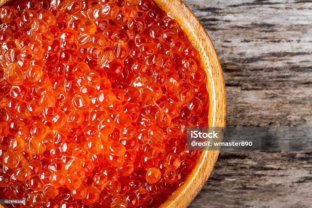 fresh red caviar in a wooden bowl closeup fresh red caviar in a wooden bowl closeup on a rustic background 2015 Stock Photo