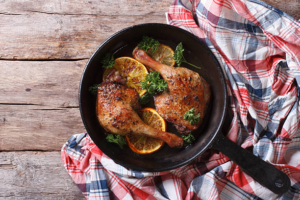 Delicious roasted duck leg with oranges close-up. top view
