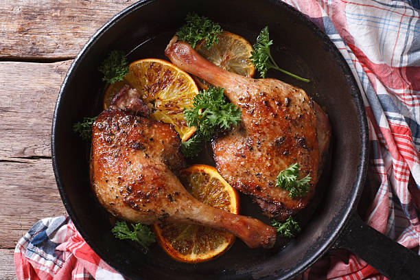 roasted duck legs in pan with citrus top view horizontal roasted duck legs in a pan with citrus closeup. horizontal view from above sauces table turkey christmas stock pictures, royalty-free photos & images