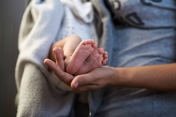 istock Mom keeps  miniature newborn feet in hands 467901644