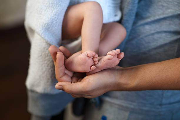 istock Mom keeps  miniature newborn leg in hand 467901790