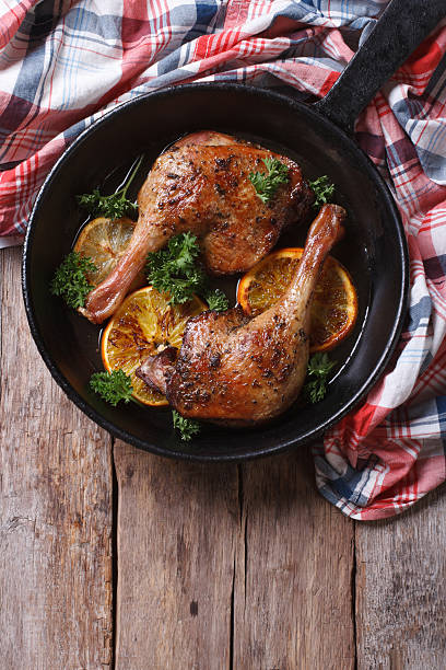istock Fried duck leg with oranges in pan vertical top view 467902410