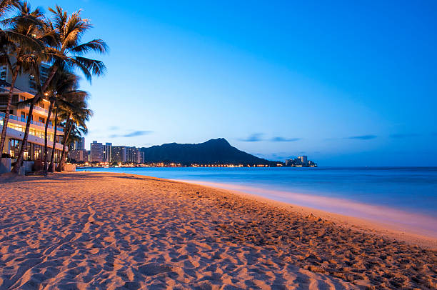 Waikiki sun rising over Diamond Head, Hawaii The sun starts to rise over the sand and shore of Waikiki Beach with Diamond Head in the background, Hawaii. honolulu stock pictures, royalty-free photos & images
