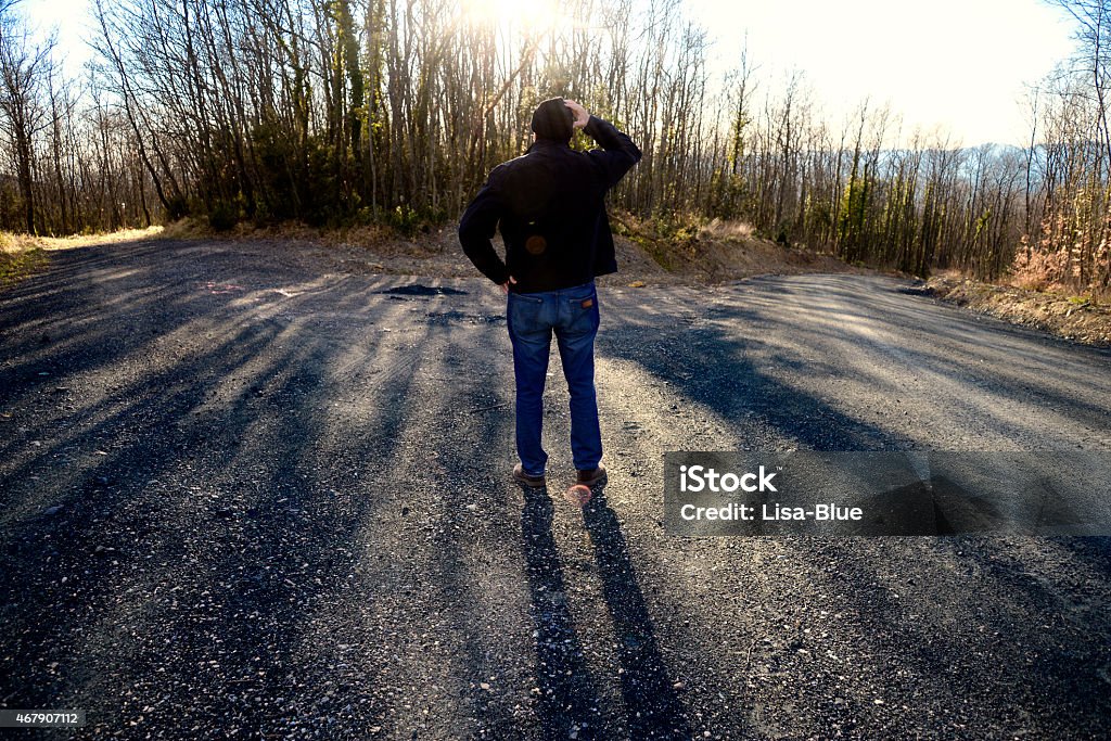 Fork in the Road Man standing at forked road. He is thinking which way to go. Vermont,USA.  2015 Stock Photo