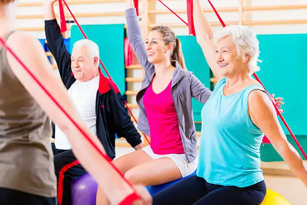 Senior people at fitness course in gym exercising with stretch band