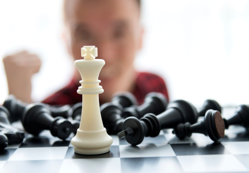 Man laughing because he win the chess. the face in back and out of focus.