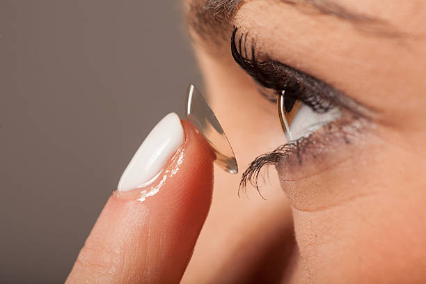 woman inserting contact lens woman putting on contact lenses lens eye stock pictures, royalty-free photos & images