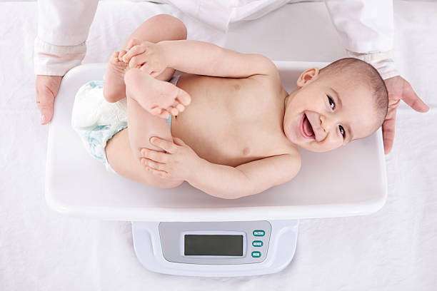 Measuring smiling beautiful comfortable little baby Measuring smiling beautiful comfortable little baby child mass unit of measurement photos stock pictures, royalty-free photos & images