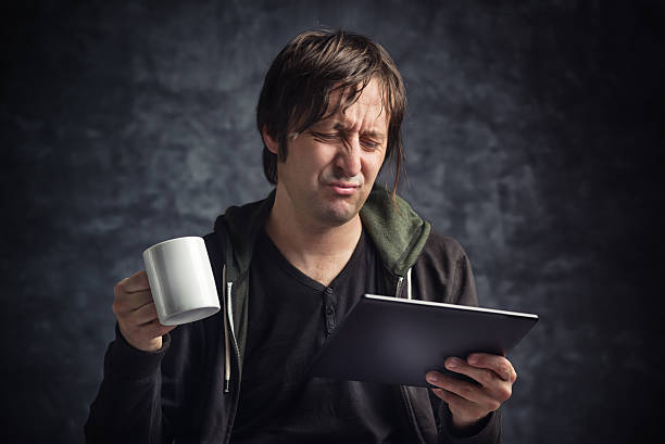 człowiek czytanie złych wieści na tablet komputer - gossip shock newspaper headline newspaper zdjęcia i obrazy z banku zdjęć