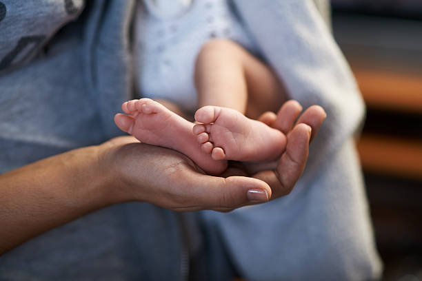 istock Mom keeps  miniature newborn feet in hands 467912788