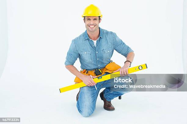 Worker Using Spirit Level While Kneeling Over White Background Stock Photo - Download Image Now