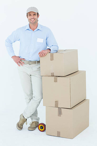 istock Confident delivery man leaning on stacked cardboard boxes 467916870