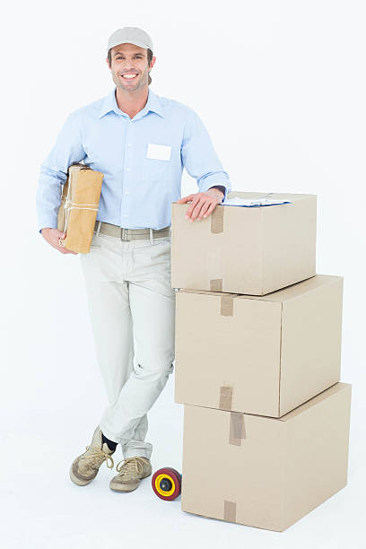 istock Handsome delivery man leaning on stacked cardboard boxes 467916876