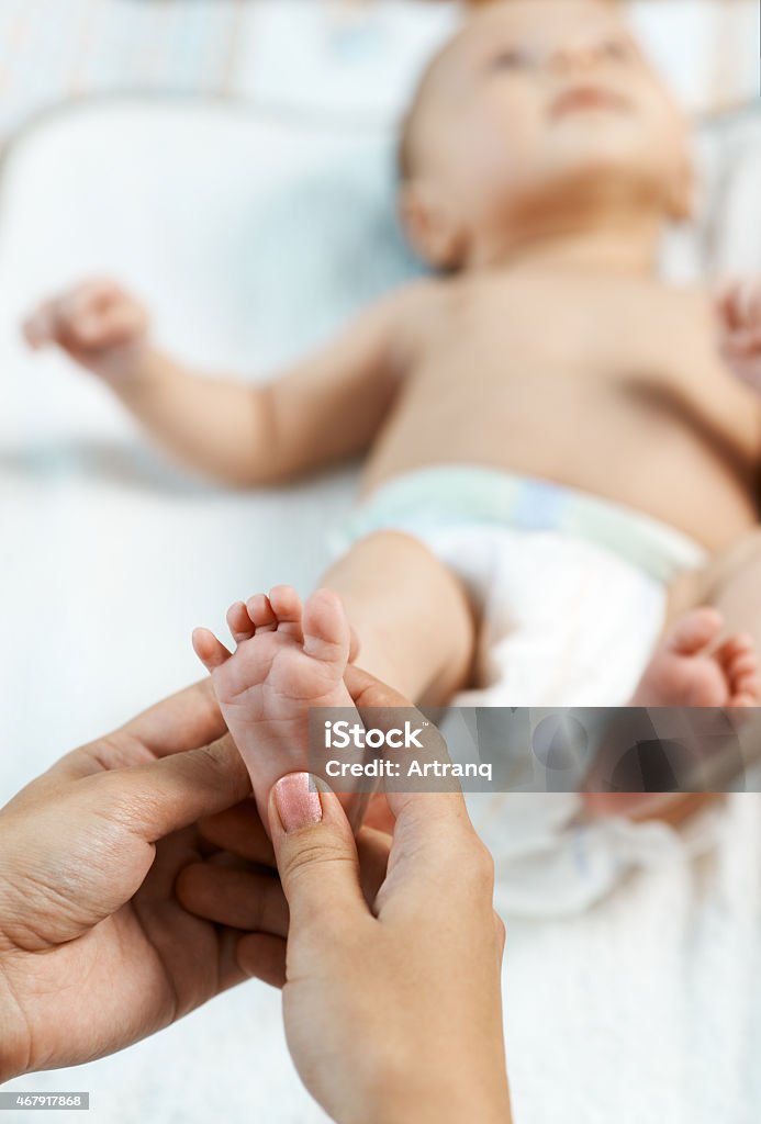 Mom checks reflex child on foot Mom checks reflex child moving her fingers on foot 2015 Stock Photo