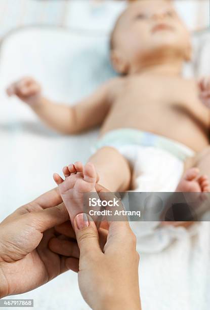 Mom Checks Reflex Child On Foot Stock Photo - Download Image Now - 2015, Baby - Human Age, Blue