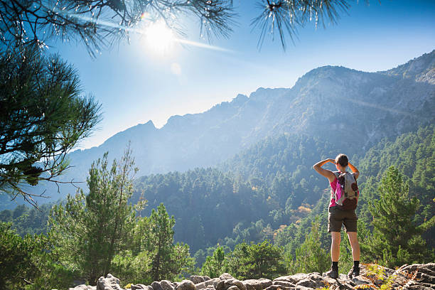 Woman on rocks and looking out to the mountains after hiking stock photo